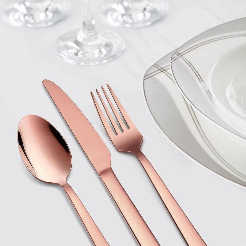 Elegant rose gold knife and cutlery set on a formal dining table.