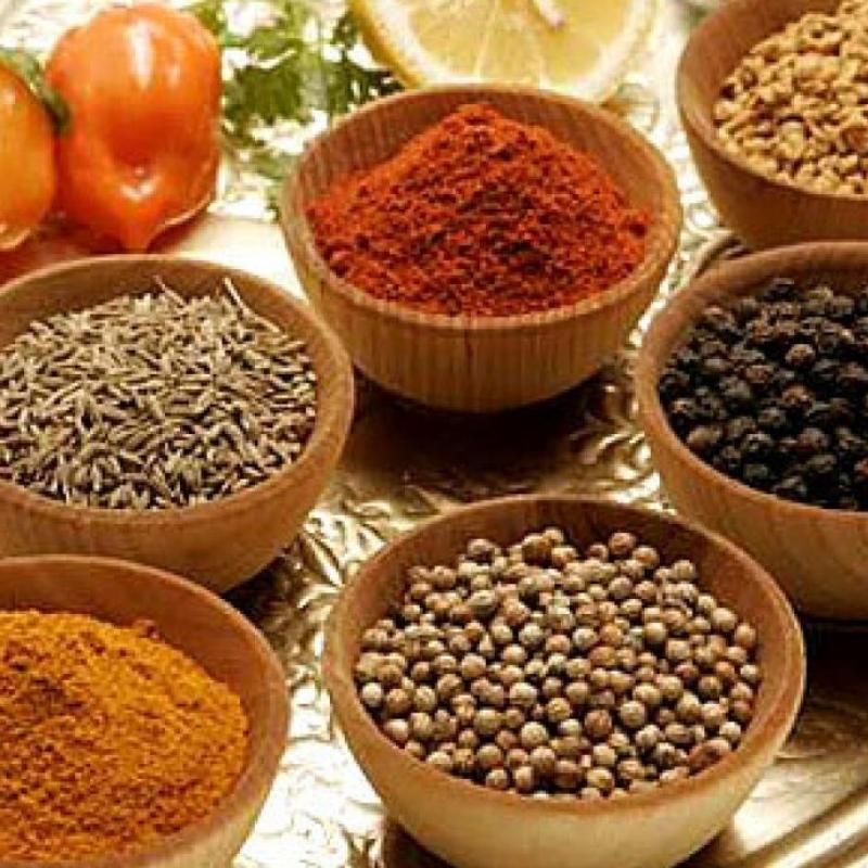 Assorted spices and seasonings in wooden bowls on a golden surface