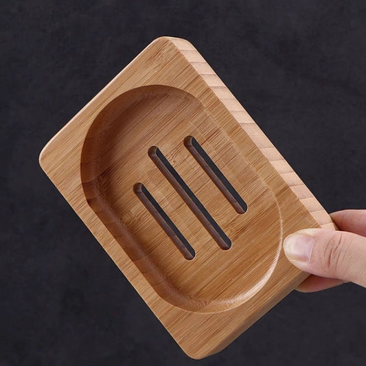 Hand holding Wooden Soap Tray Dish made of bamboo with three drainage slots, ideal for eco-conscious bathroom accessories.
