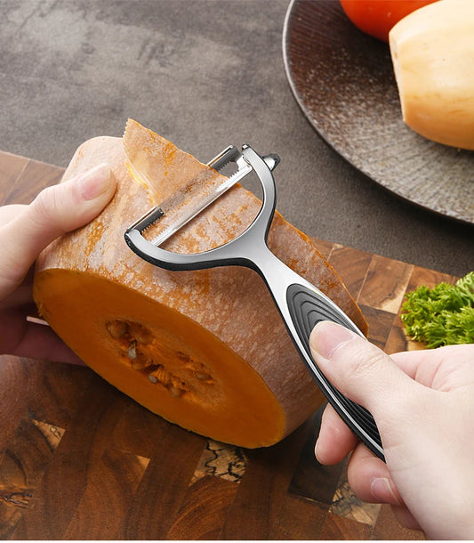 Stainless steel vegetable peeler effortlessly slicing through pumpkin skin. Ergonomic handle ensures a firm grip for efficient peeling in the kitchen.