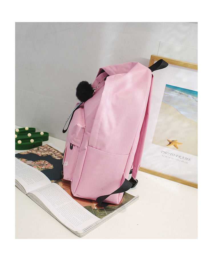 Pink Casual Korean Canvas Backpack displayed on a desk, showcasing its side profile and spacious interior for daily use.