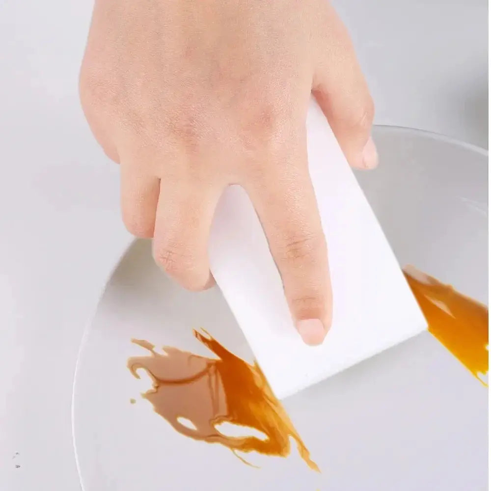 Close-up of 3Pcs White Magic Sponge removing sauce stains from a plate. Durable cleaning sponge for kitchen and home use.