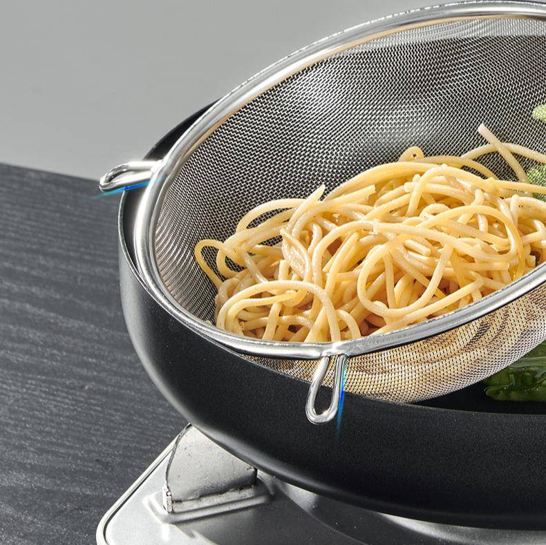 Double Ear Food Strainer 20CM straining cooked spaghetti over a pot, highlighting its sturdy dual ear support and efficient draining capability.