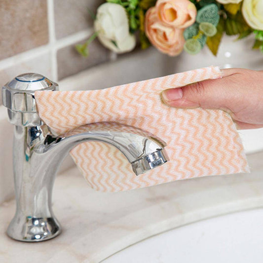 Peach-colored Non Woven Cleaning Cloth wiping a bathroom faucet, demonstrating efficient and streak-free surface cleaning.