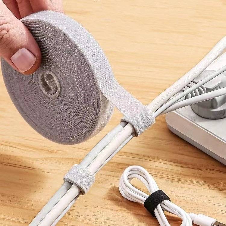 3M Cable Tape - Reusable Fastening secures multiple white cables with adjustable nylon straps. Ideal for organizing cords on desks or power strips.
