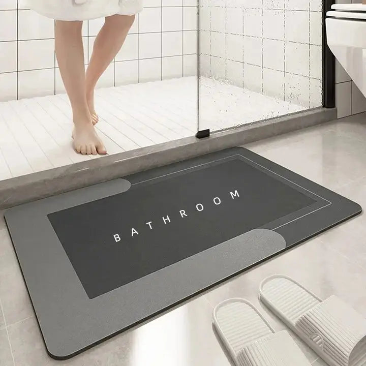 Dark grey rectangular absorbent bathroom mat with 'BATHROOM' text, positioned outside a shower to keep wet floors dry and slip-free.