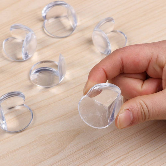 Silicone Table Corner Guard 4PCS shown on wooden surface with one piece held in hand, highlighting soft clear silicone and adhesive backing.