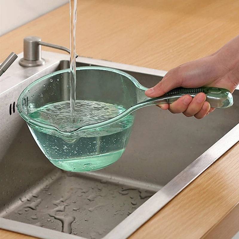 Transparent plastic ladle with ergonomic handle, pouring water into a sink. Ideal for kitchen use, lightweight and durable.