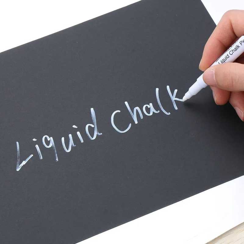 White liquid chalk pen writing on black surface, showcasing vibrant, erasable ink for precise drawing or labeling use.