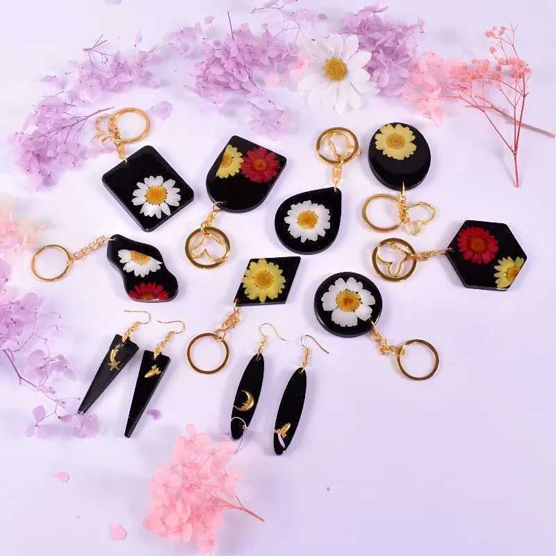 Assorted resin jewelry pieces made using the Earring Pendant Silicone Mold, featuring embedded flowers in earrings and keychains.