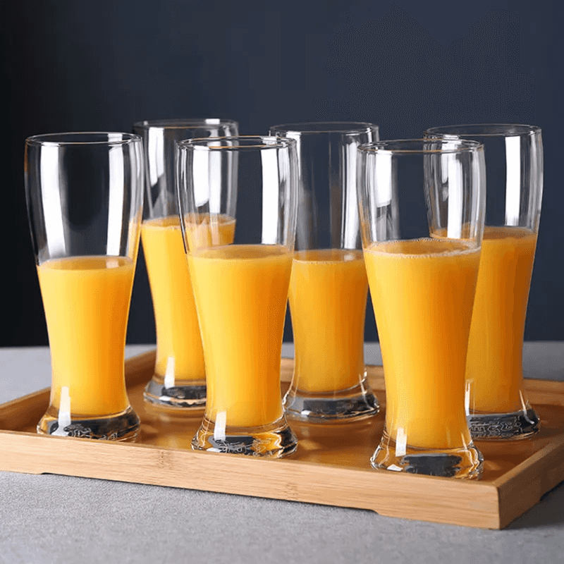 Set of six Mocktail Beer Tumbler Glasses 400 ml filled with orange juice on a wooden tray, perfect for home and garden drinkware use.