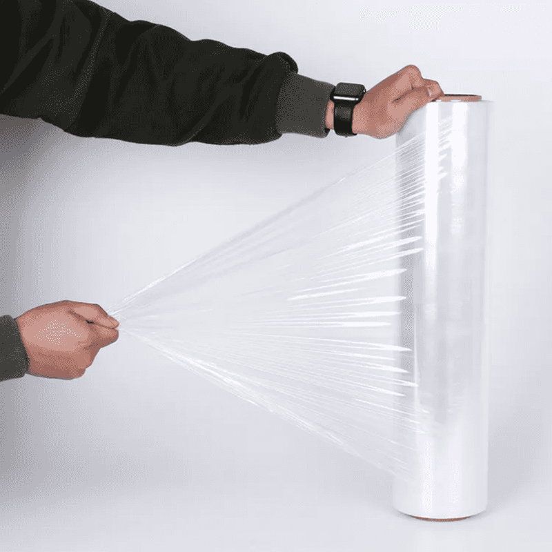 Stretchable Shrink Wrap Roll being pulled by hand, showcasing durability for bundling and pallet wrapping in home or industrial settings.