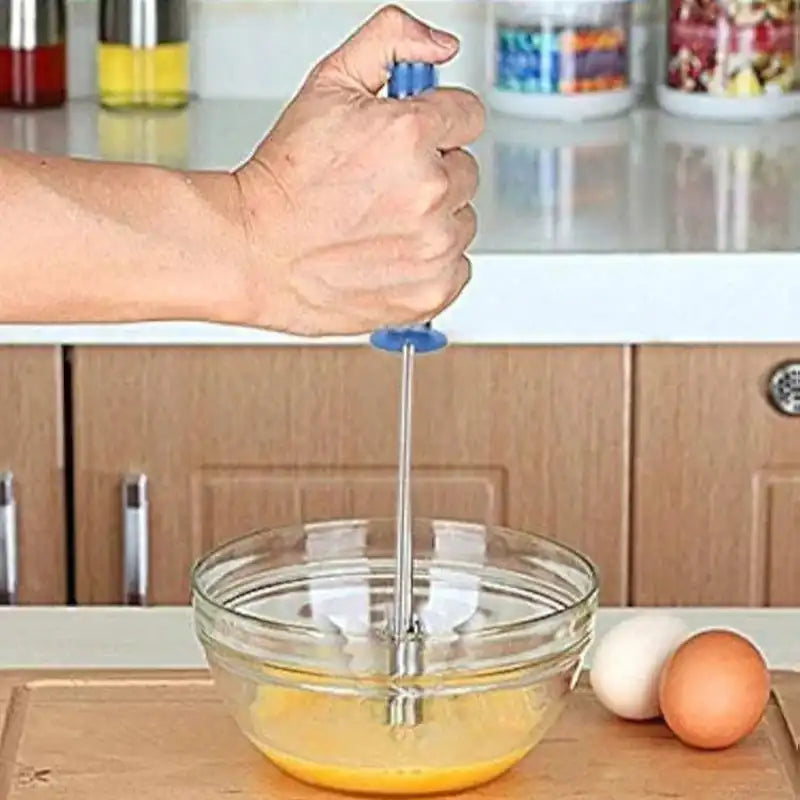 Person using stainless steel hand mixer to beat eggs in a glass bowl. Ergonomic handle design perfect for home kitchen use.