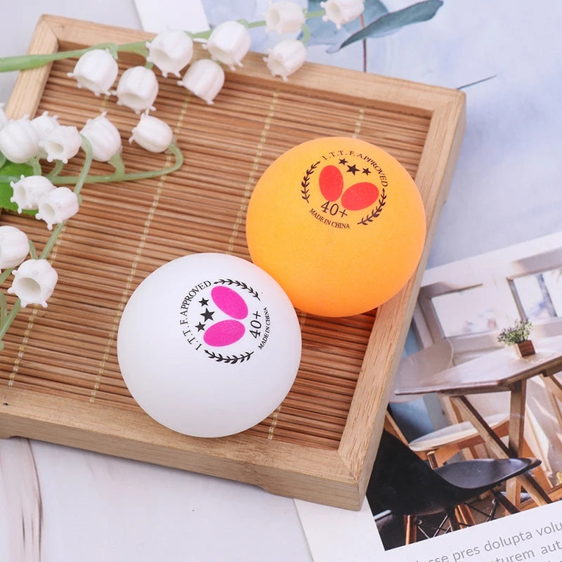 Butterfly 40+ white and orange table tennis balls on wooden tray, designed for durability and precision. Table tennis balls best price in Sri Lanka.