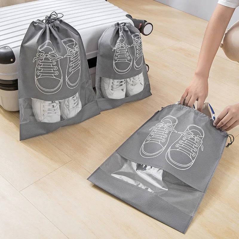 Durable grey shoe storage bags for travel, holding white sneakers with drawstring closure and transparent window for easy identification.