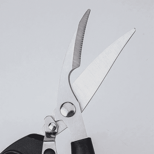 Close-up of sharp stainless steel blades on kitchen scissor designed for cutting chicken bones, meat, and herbs with precision.