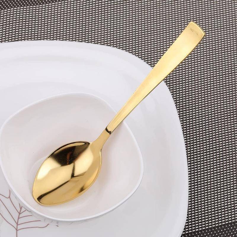 Single gold table spoon with a sleek handle on a white ceramic plate, showcasing premium flatware. Shop Gold Table Spoons Set Online in Sri Lanka.