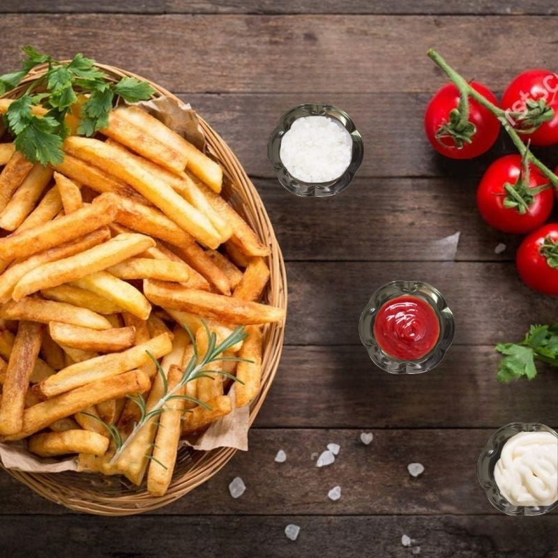 Mini flower-shaped stainless steel dipping bowls filled with sauces beside fries and tomatoes, perfect for stylish table presentations.