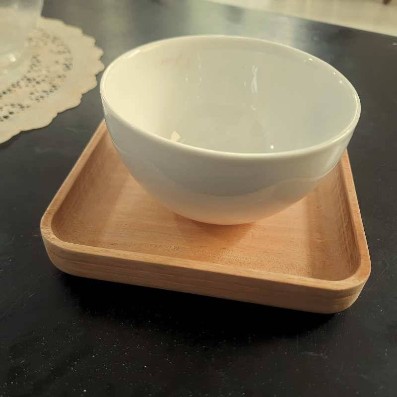 Square wooden serving tray holding a white ceramic bowl, showcasing its use in kitchen and dining decor.
