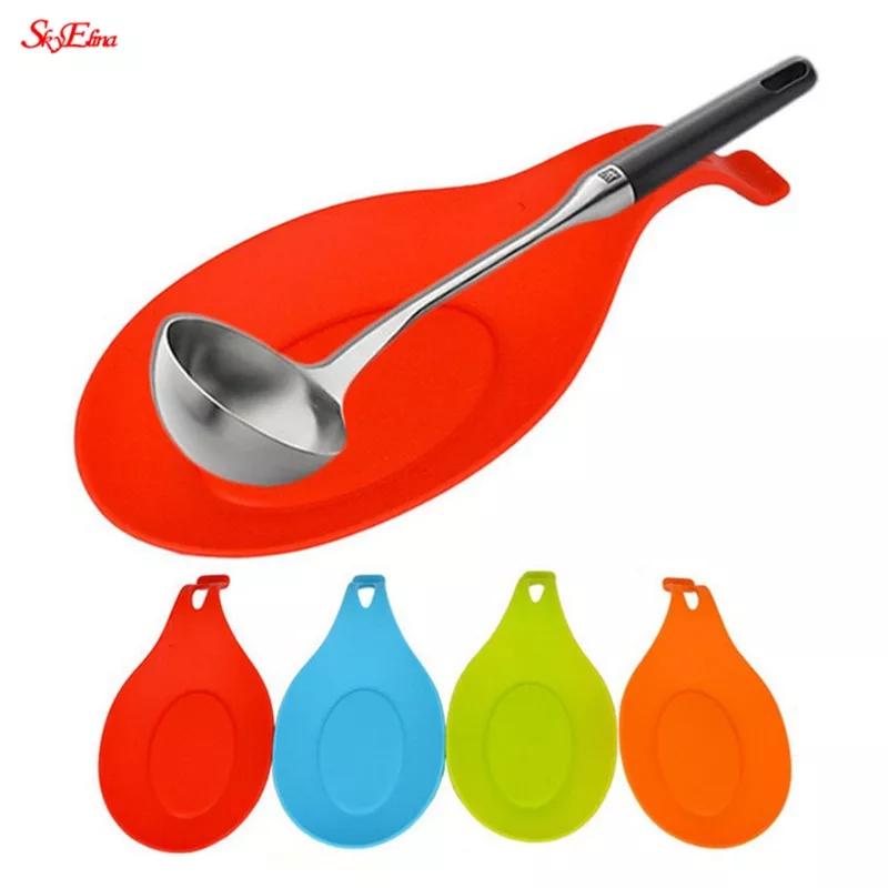 Set of colorful Silicone Spoon Rest Pads with a ladle on the red one. Durable, food-grade kitchen accessory for clean cooking surfaces.