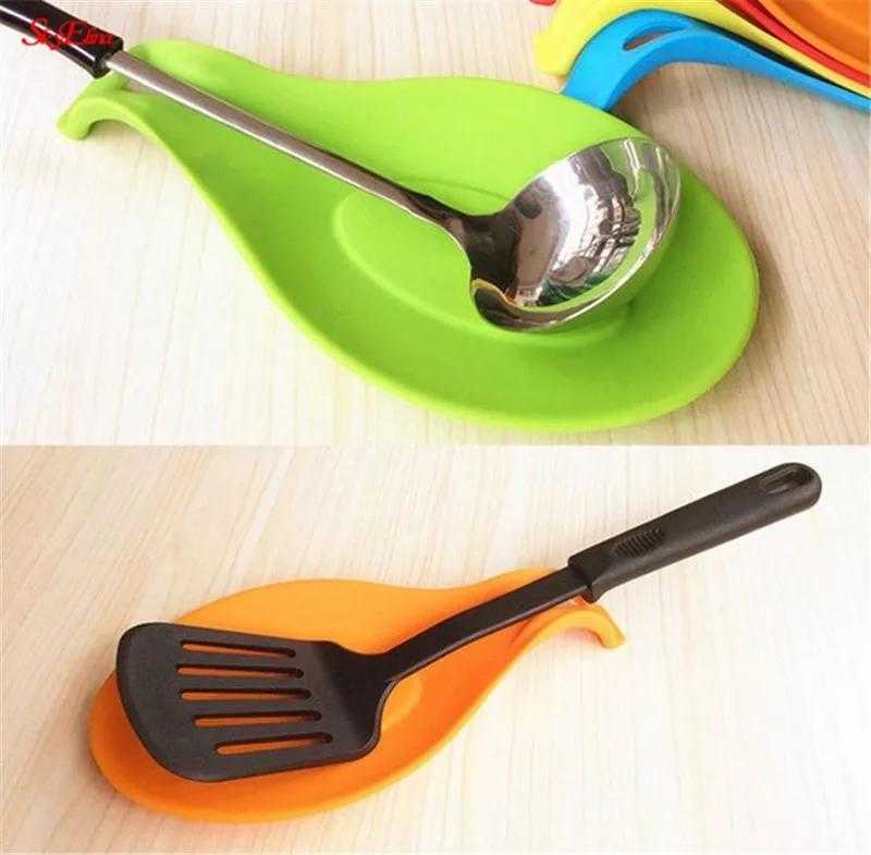 Silicone Spoon Rest Pad - Heat & Spill Resistant in green and orange holding kitchen utensils. Ideal for hygienic and convenient cooking use.