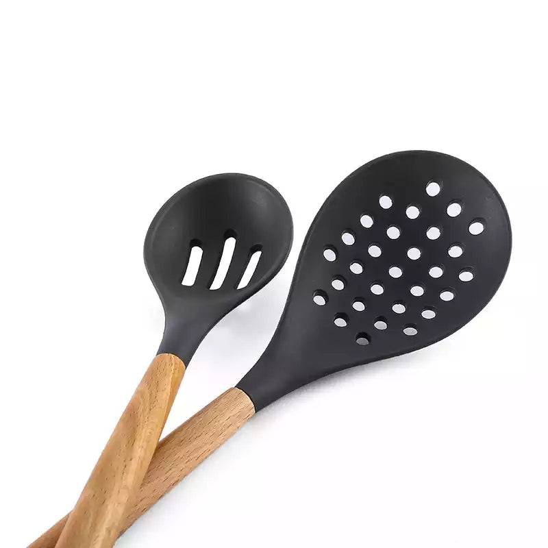 Close-up of grey silicone slotted spoon and ladle with wooden handles, part of 12-piece heat-resistant kitchen utensil set.