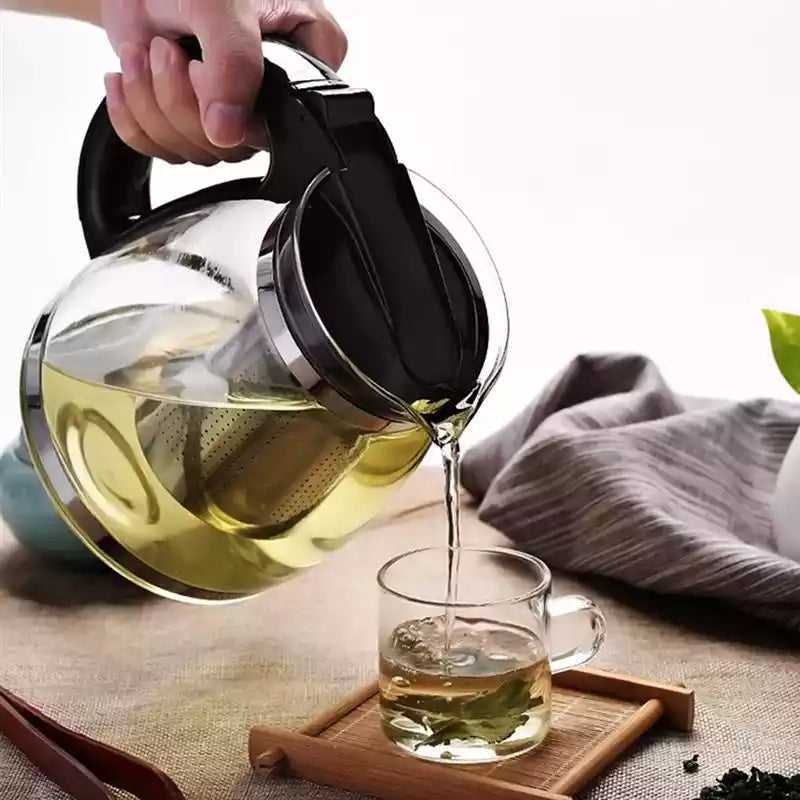 1L glass teapot with detachable infuser pouring herbal tea into a glass cup, ideal for tea, coffee, and herbal infusions.