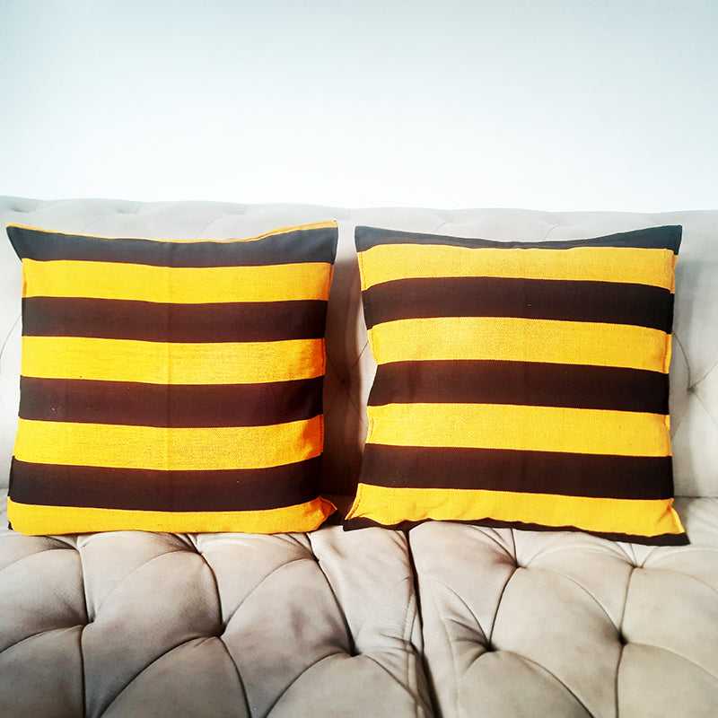Pair of Striped Handloom Cushion Covers in black and orange cotton on a tufted sofa, perfect for stylish living room or bedroom decor.