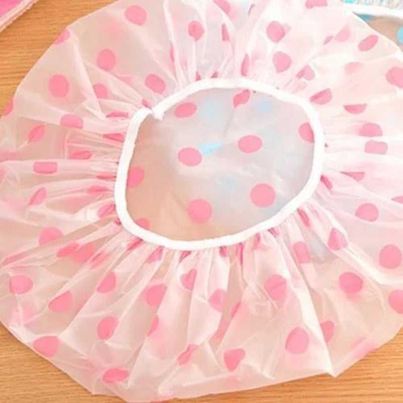 Pink polka dot waterproof shower cap with elastic edge, displayed flat on a wooden surface. Reusable and suitable for all hair types.