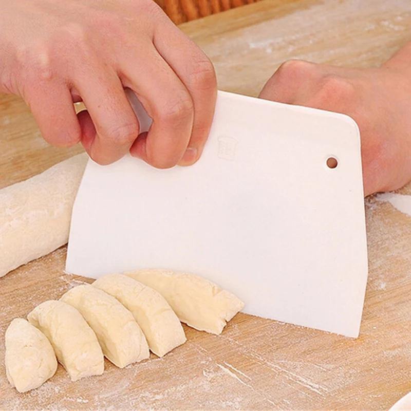 Plastic pizza dough scraper trapezoid cutter slicing dough on wooden board. Ideal for cake levelling and icing smoothing in Sri Lanka kitchens.